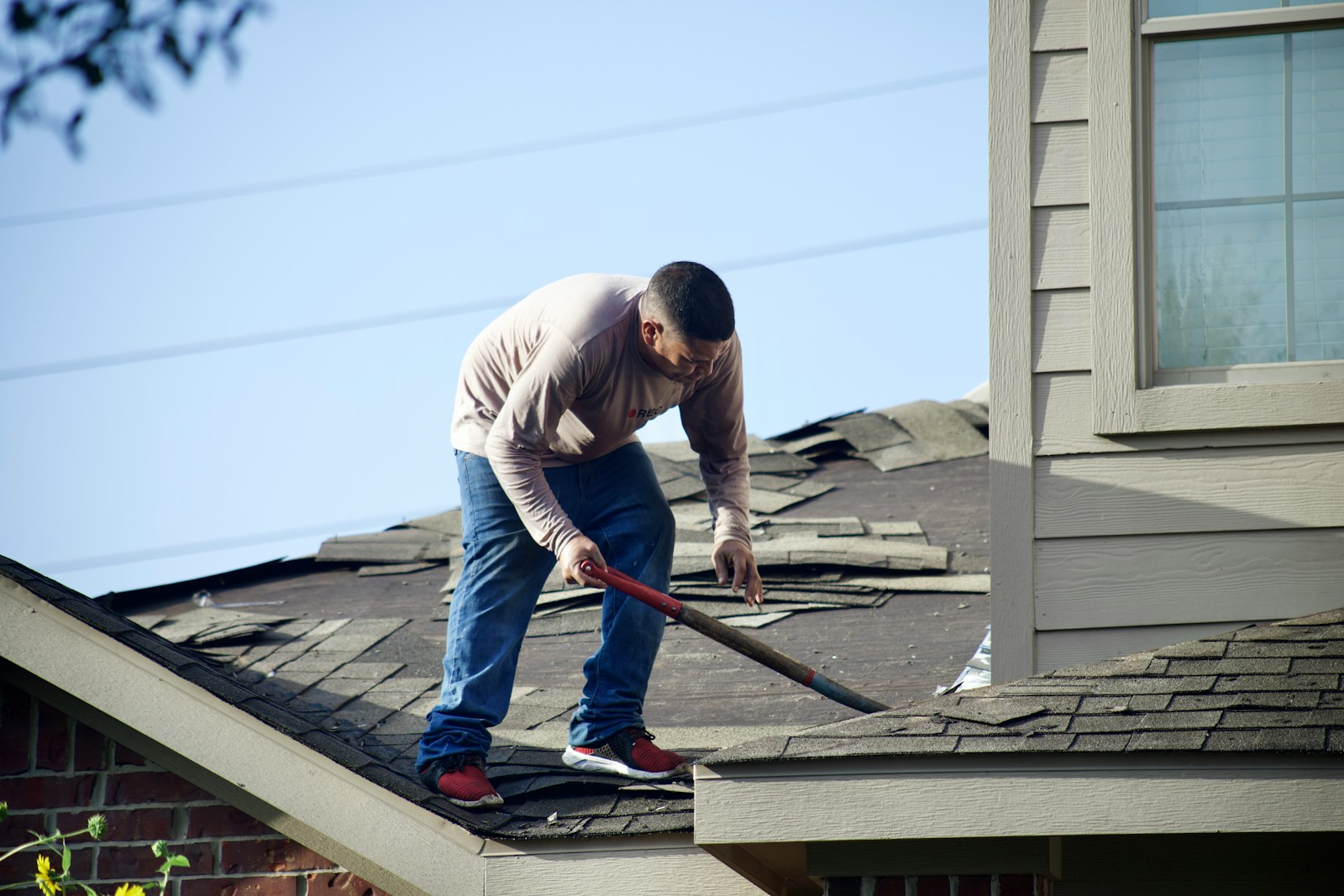 a man with a hammer on top of a roof doing roof repairs
